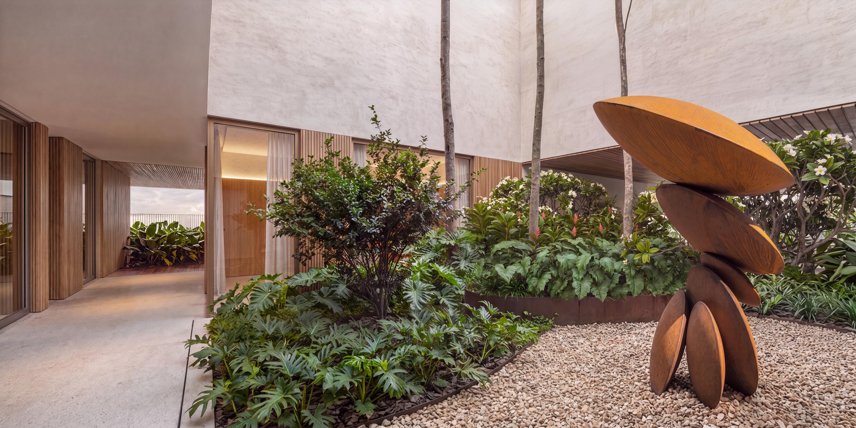 Átrio interno com vegetação tropical e escultura